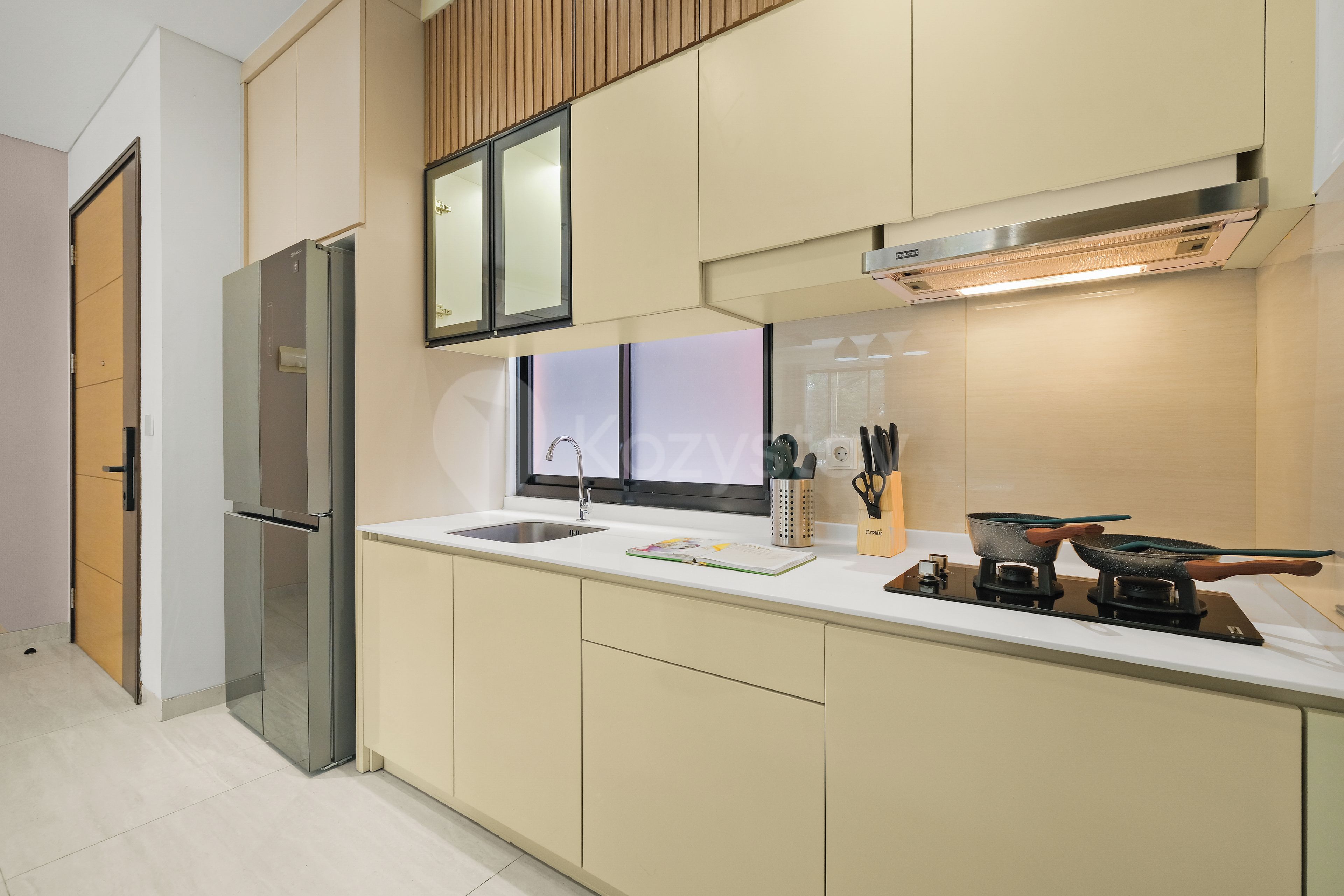 A modern kitchen with a stainless steel refrigerator, a built-in oven, a sink, and a stove.