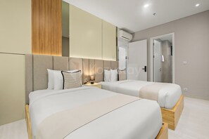 Ein modernes Hotelzimmer mit zwei Betten, einem Nachttisch mit Lampe, einer Klimaanlage und einer Tür zu einem Badezimmer.