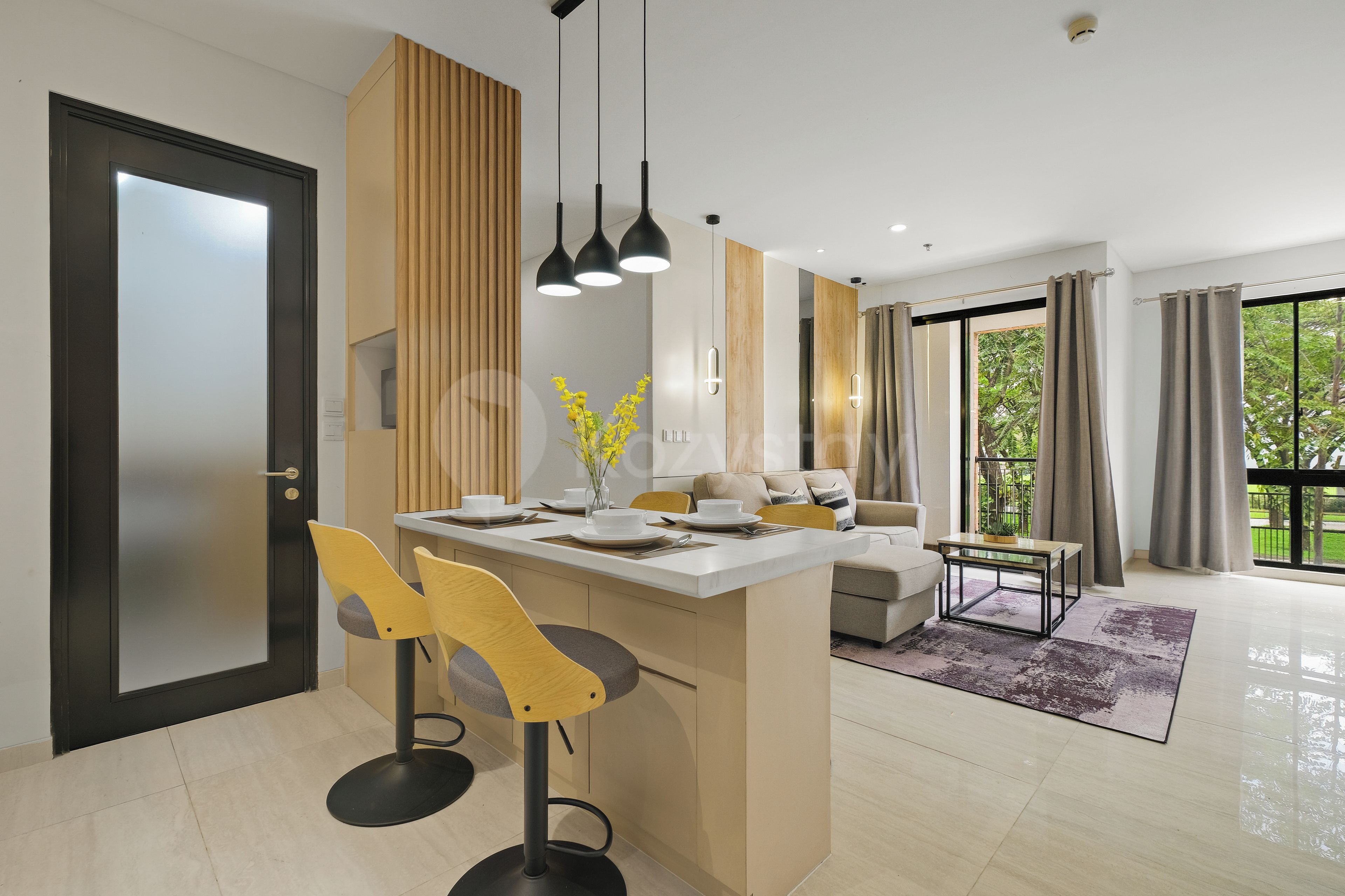 A modern kitchen with a central island, bar stools, and pendant lighting.