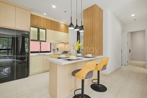 A modern kitchen with a central island, pendant lighting, and a view of the outdoors. - Noma by Kozystay - Alam Sutera (Tangerang Selatan)