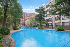 A swimming pool surrounded by trees and modern buildings. - Noma by Kozystay - Alam Sutera (Tangerang Selatan)