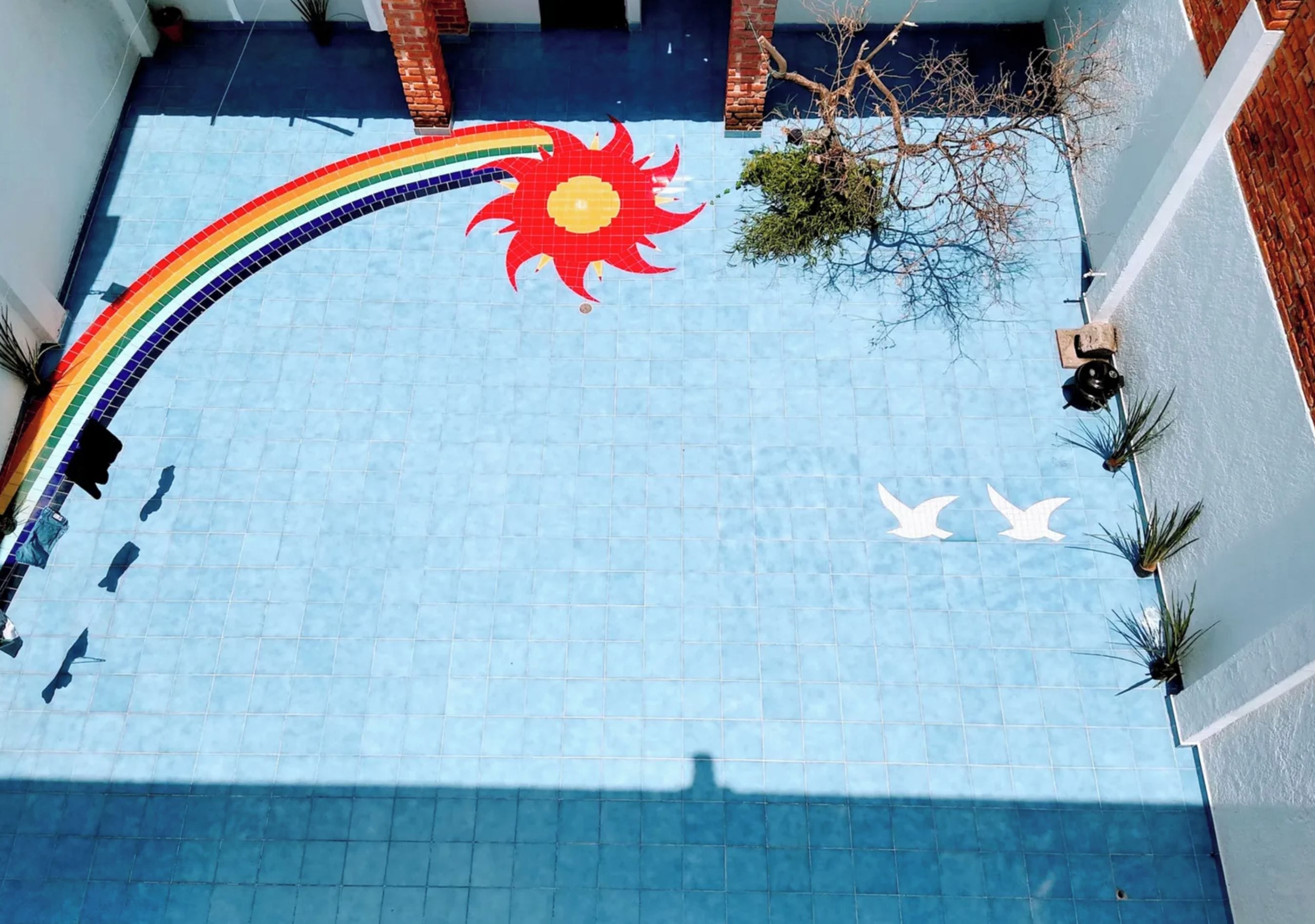 A tiled floor with a rainbow, sun, and birds.