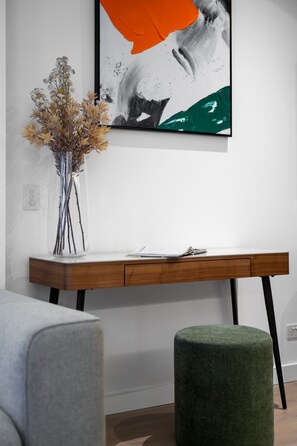 Una camera moderna con una scrivania in legno, un vaso con fiori secchi e un quadro astratto incorniciato.