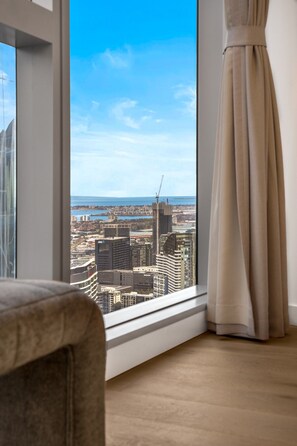 A room with a large window offering a city view, a chair, and a curtain. - Sky-High Lv50 Escape| Pool Gym Sauna| Near Skybus (Melbourne)