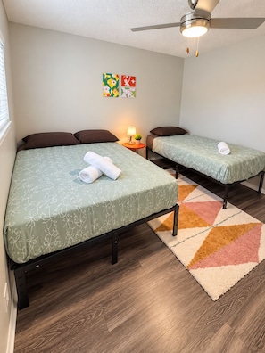 A hotel room with two beds, a ceiling fan, a small table with a lamp, and a colorful rug. - SOCO 2BDR-Shoping, Dining, Music - Apartment (Austin)