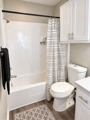 A bathroom with a bathtub, toilet, and shower curtain. - SOCO 2BDR-Shoping, Dining, Music - Apartment (Austin)