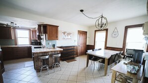 A kitchen with a bar area, a dining table, and a coffee machine. - Large Apartment Between Bates, St. Mary’s & CMMC (Lewiston)