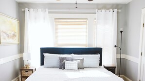 A bedroom with a bed, a ceiling fan, a window with blinds, and a nightstand. - Large Apartment Between Bates, St. Mary’s & CMMC (Lewiston)