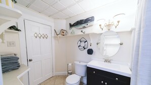 A bathroom with a white toilet, a black vanity, a white sink, and a shower area. - Large Apartment Between Bates, St. Mary’s & CMMC (Lewiston)
