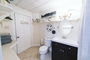 Ein Badezimmer mit einer weißen Toilette, einem schwarzen Waschtisch, einem weißen Waschbecken und einer Duschkabine.