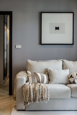 A modern living room with a grey sofa, a framed picture, and a wooden floor. - Bang Tao 10 Min to Beach Elevated Views (Tambon Choeng Thale)