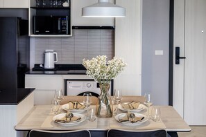 A modern kitchen with a dining table set for two, a microwave, a coffee maker, and a washing machine. - Bang Tao 10 Min to Beach Elevated Views (Tambon Choeng Thale)