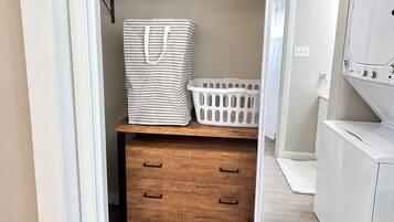 A closet with a mirrored door, a wooden dresser, and a laundry basket.