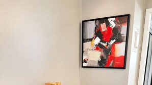 Eine moderne Bar mit einem runden Tisch, zwei Barhocker und einem gerahmten abstrakten Gemälde an der Wand.