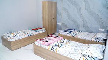 Un dormitorio con dos camas de madera, paredes con diseño de mármol y un armario.