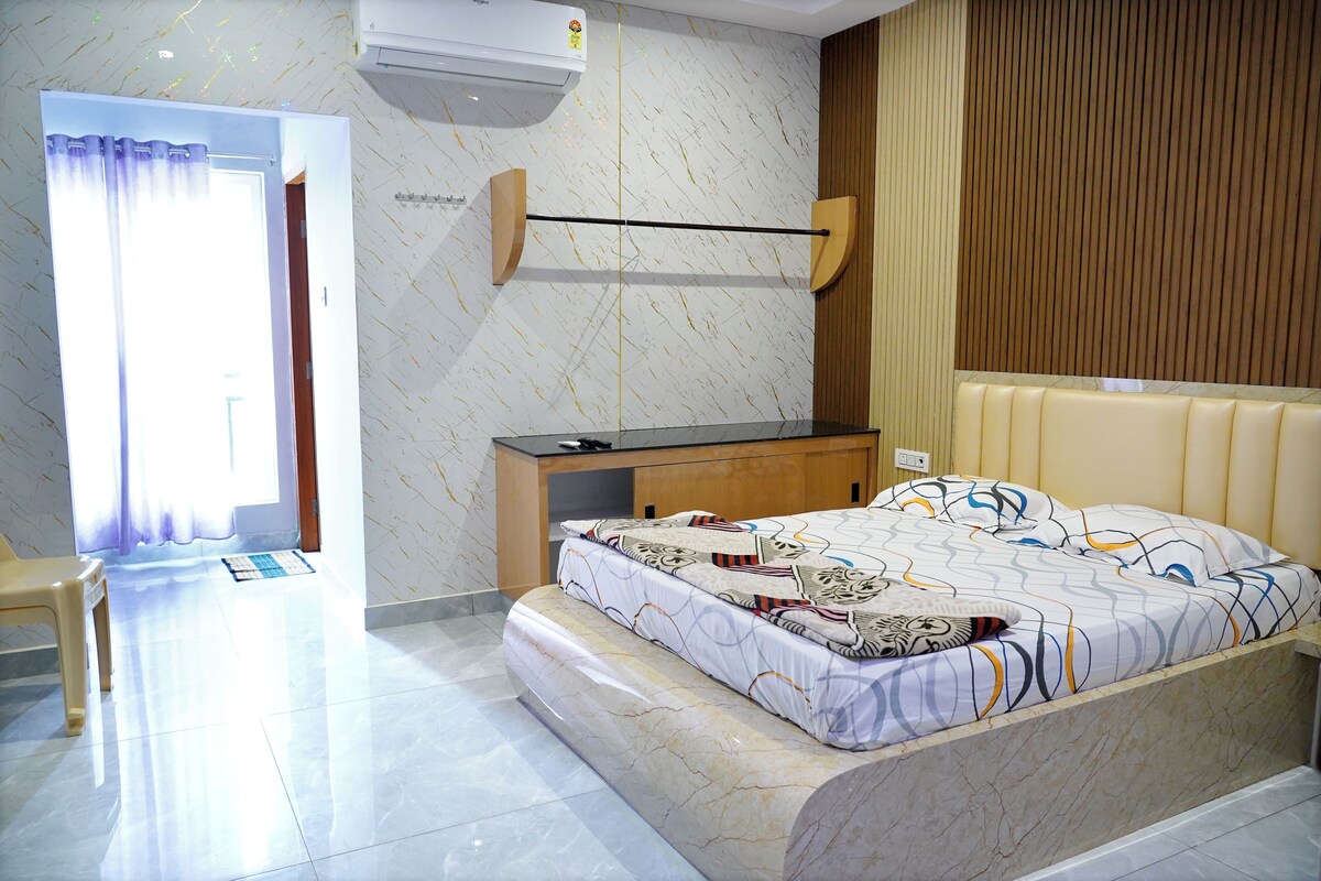 A hotel room with a bed, a desk, a chair, and a bathroom visible through an open door.