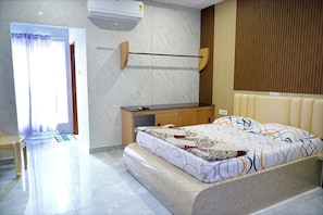 A hotel room with a bed, a desk, a chair, and a bathroom visible through an open door.