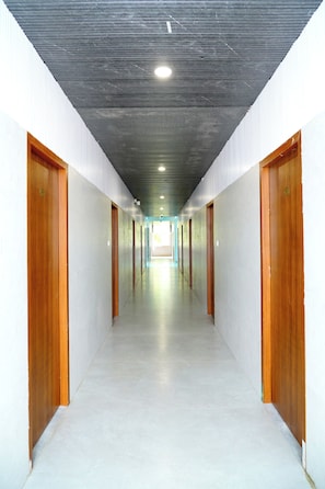 A corridor with doors on both sides, a tiled floor, and a ceiling with recessed lighting.