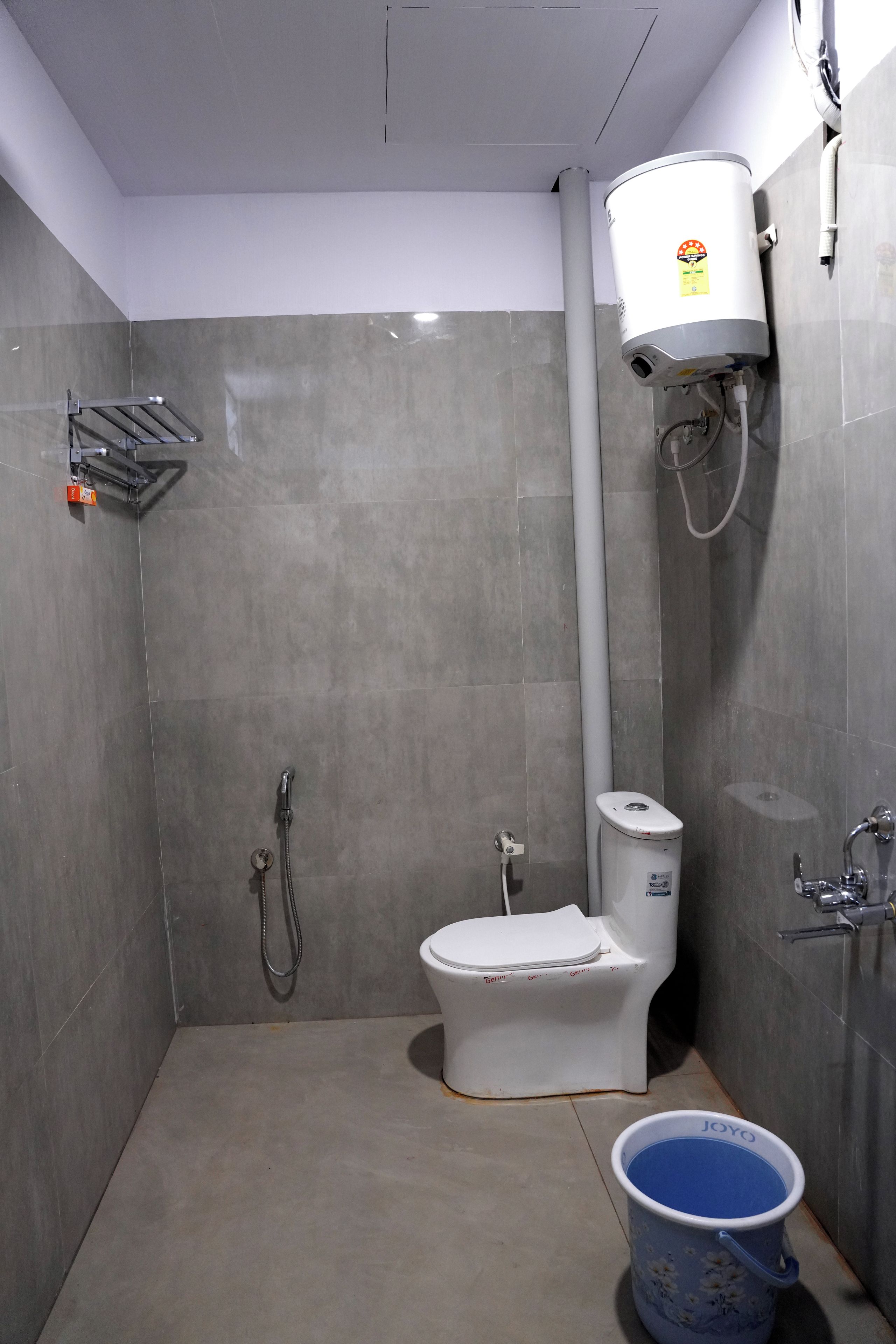 A bathroom with a toilet, shower, and a water heater.