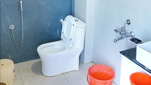 A bathroom with a toilet, a shower, and a sink. There are two buckets on the floor. - SRT Convention & Hotel (Tadpatri Rural)