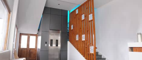 A modern interior with a staircase, a kitchen area, and a door leading to another room.