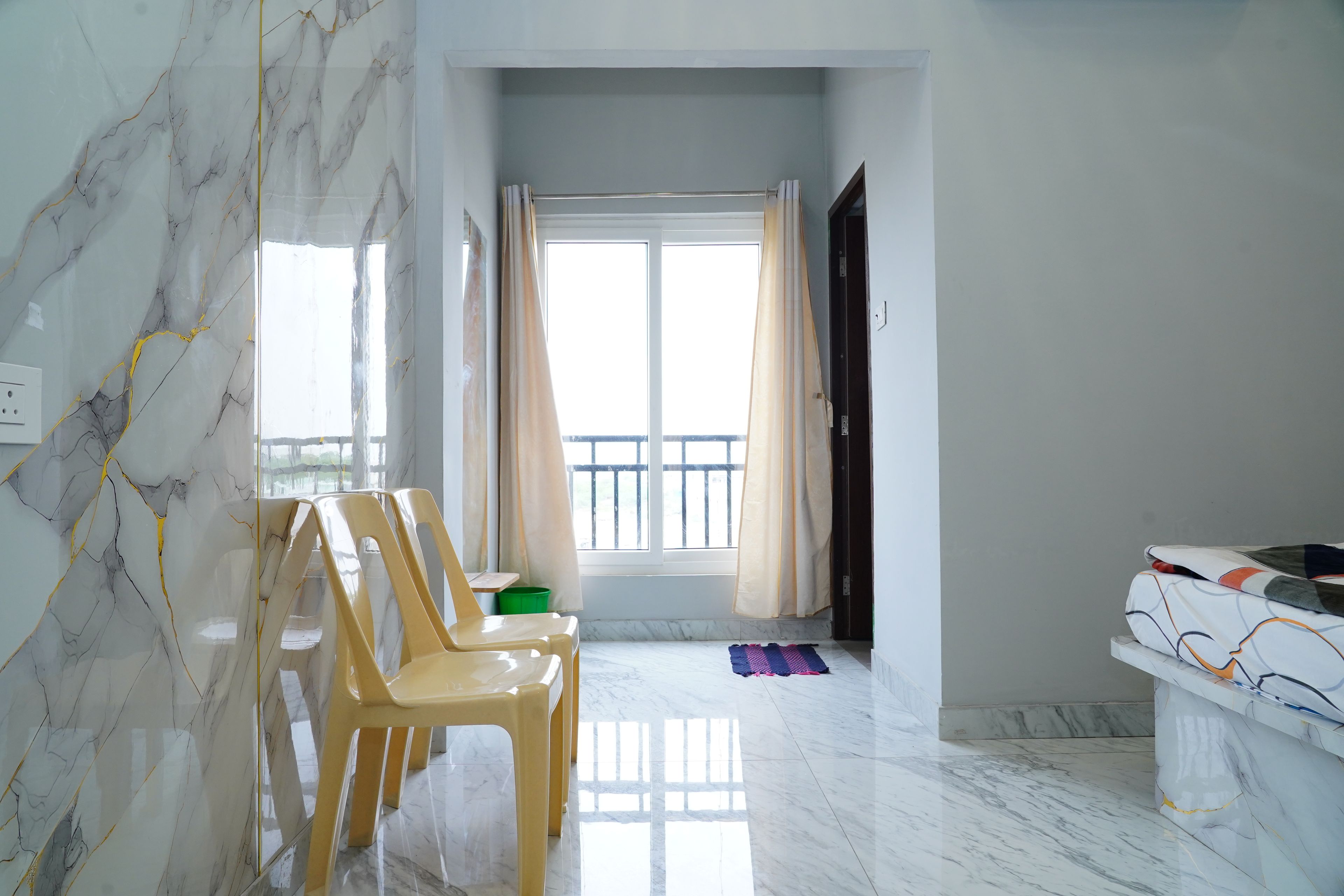 Une pièce dotée d’un sol en marbre, d’une fenêtre avec des rideaux et d’un lit recouvert d’une couvre-lit à motifs.