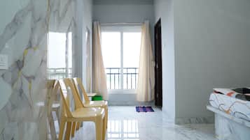Habitació amb sòl de marbre, finestra amb cortines i llit amb estriatges decoratius.