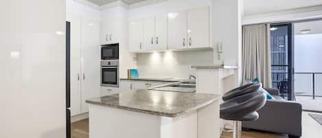 A modern kitchen with white cabinets, a granite countertop, and a built-in oven.