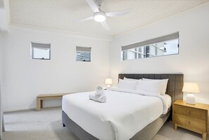 A hotel room with a bed, a ceiling fan, a nightstand, a bench, and two wall-mounted windows. - 10/21 The Esplanade - A Coastal Escape in the Heart of Cotton Tree (Maroochydore)
