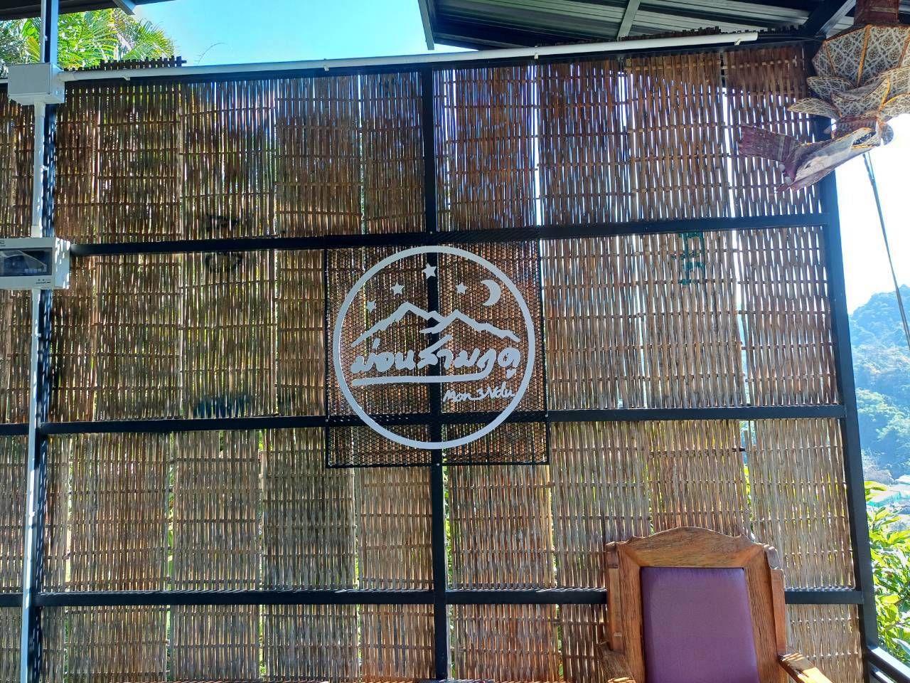 A bamboo fence with a circular logo featuring a mountain and text.