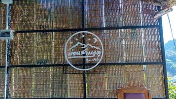 A bamboo fence with a circular logo featuring a mountain and text.