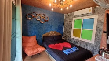 A bedroom with a bed, a chair, a wall-mounted air conditioner, and a window with colored panels.