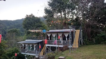 Ein zweistöckiges Gebäude mit Balkon, umgeben von Grünflächen und Hügeln.