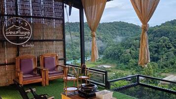 An outdoor seating area with chairs and a table, overlooking a lush green landscape.