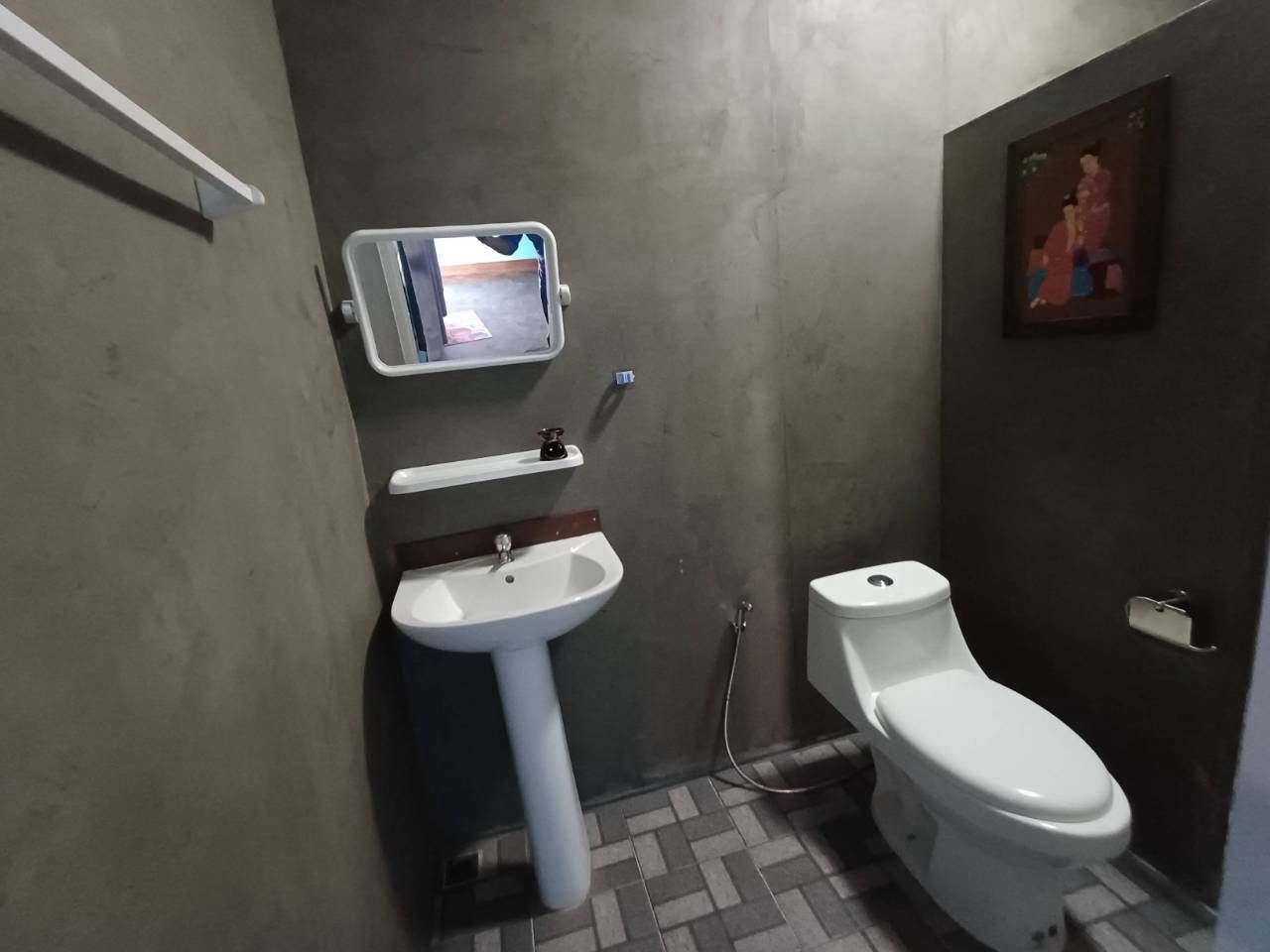 A bathroom with a white sink, toilet, and a small mirror with a digital display.
