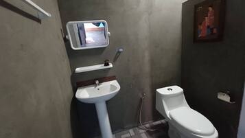 A bathroom with a white sink, toilet, and a small mirror with a digital display.