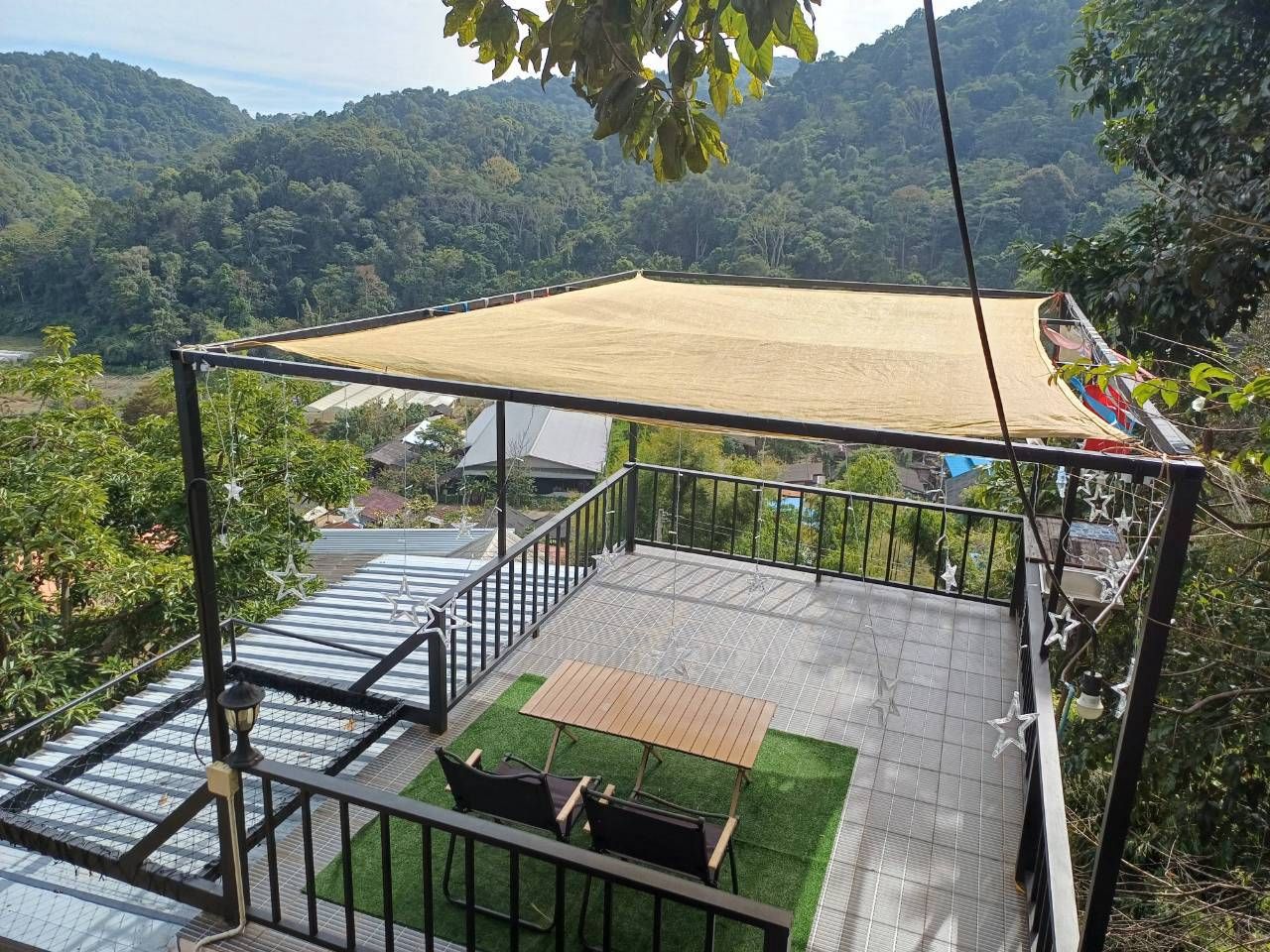 A balcony with a view of a mountainous landscape, a table and chairs, and a hanging chair.