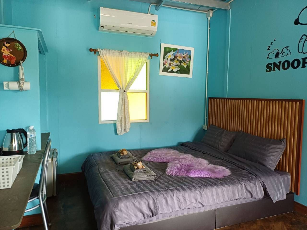 A bedroom with a bed, a desk, and a window with curtains.
