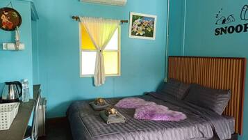 A bedroom with a bed, a desk, and a window with curtains.