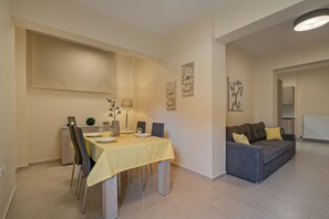 Ein Essbereich mit einem Tisch für vier Personen, einer Couch und Kunstwerken an den Wänden.