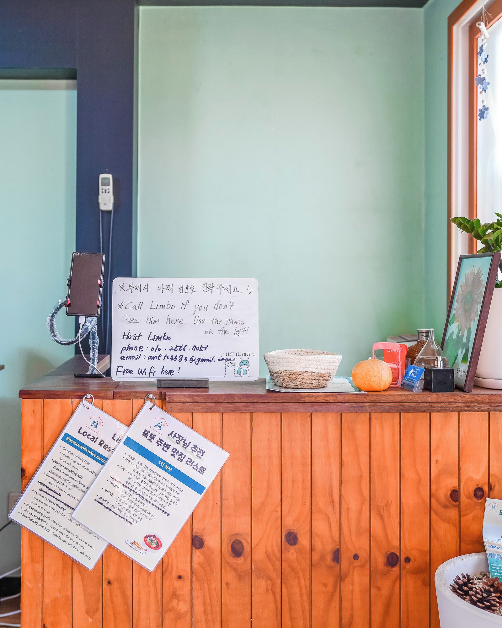 A reception desk with a signboard, a phone, a menu, and a framed picture.