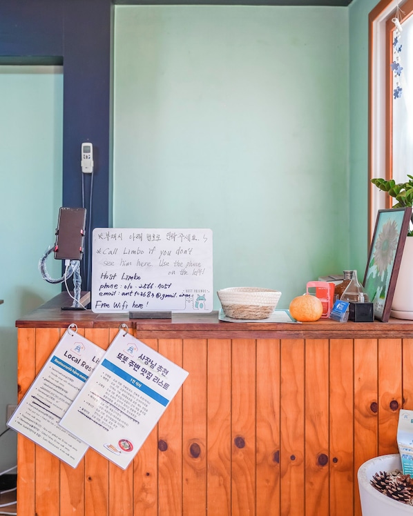 A reception desk with a signboard, a phone, a menu, and a framed picture.