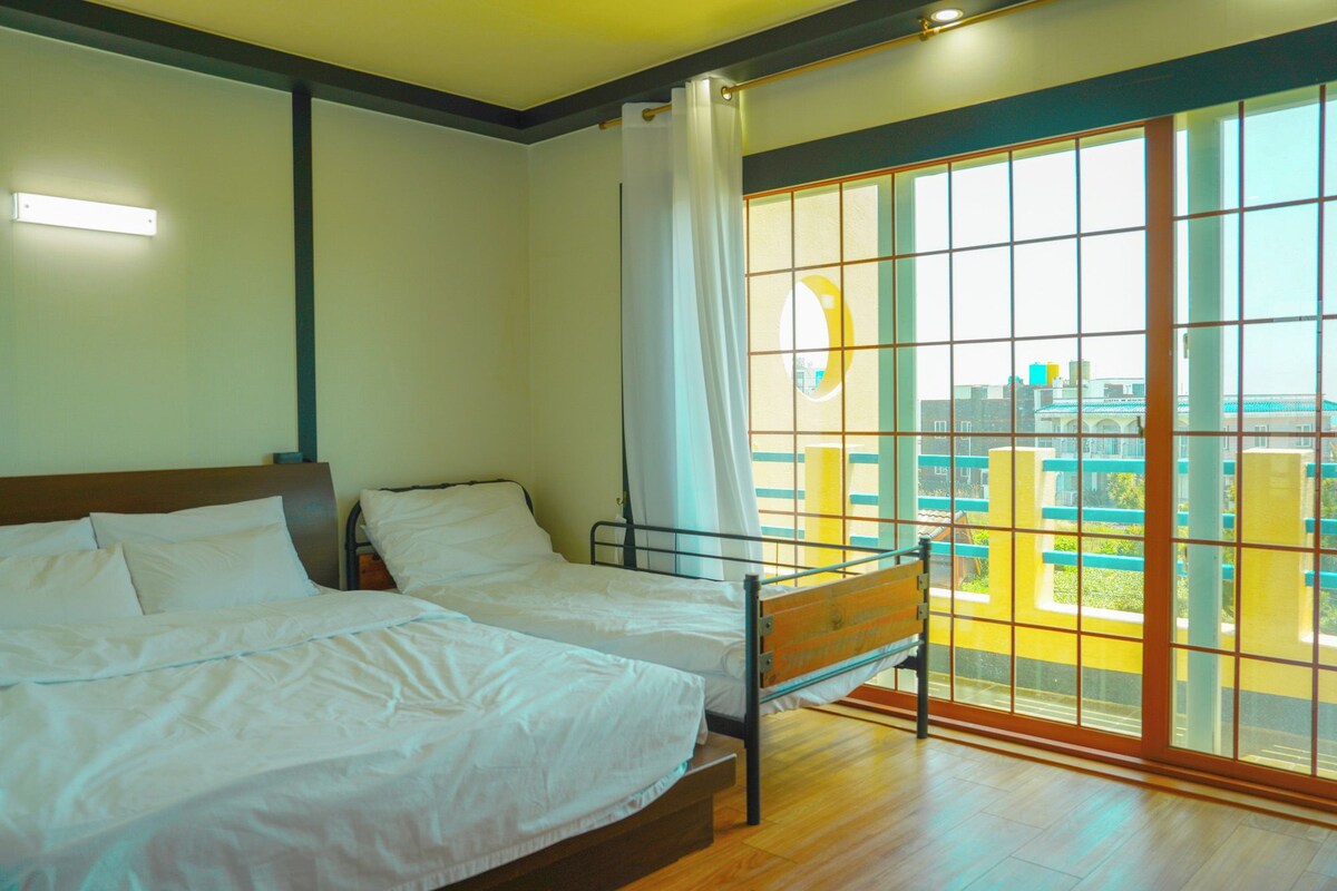 Quarto com uma cama, janela com vista para edifícios e cortina.
