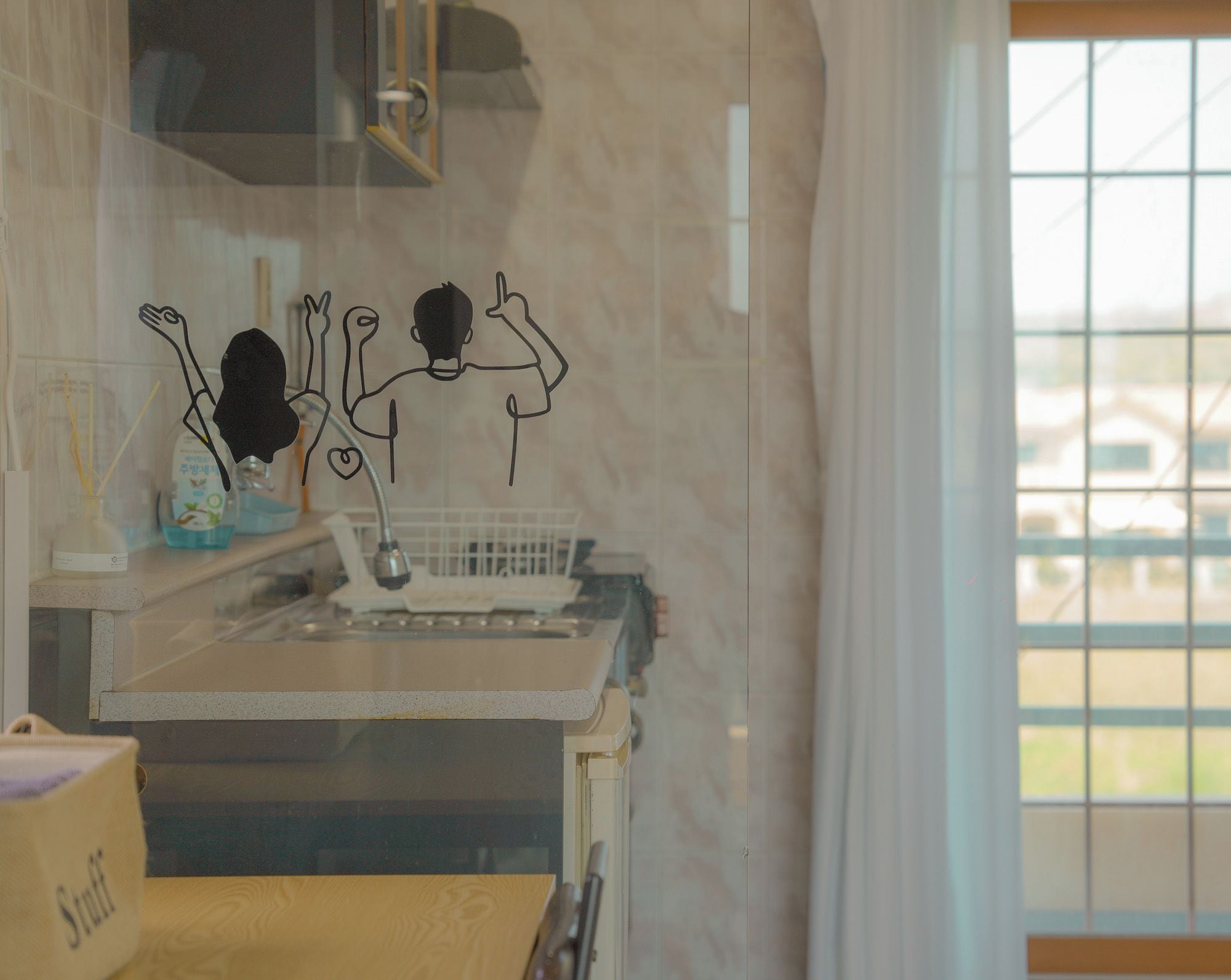 A kitchen with a window, a sink, and a countertop with various items.