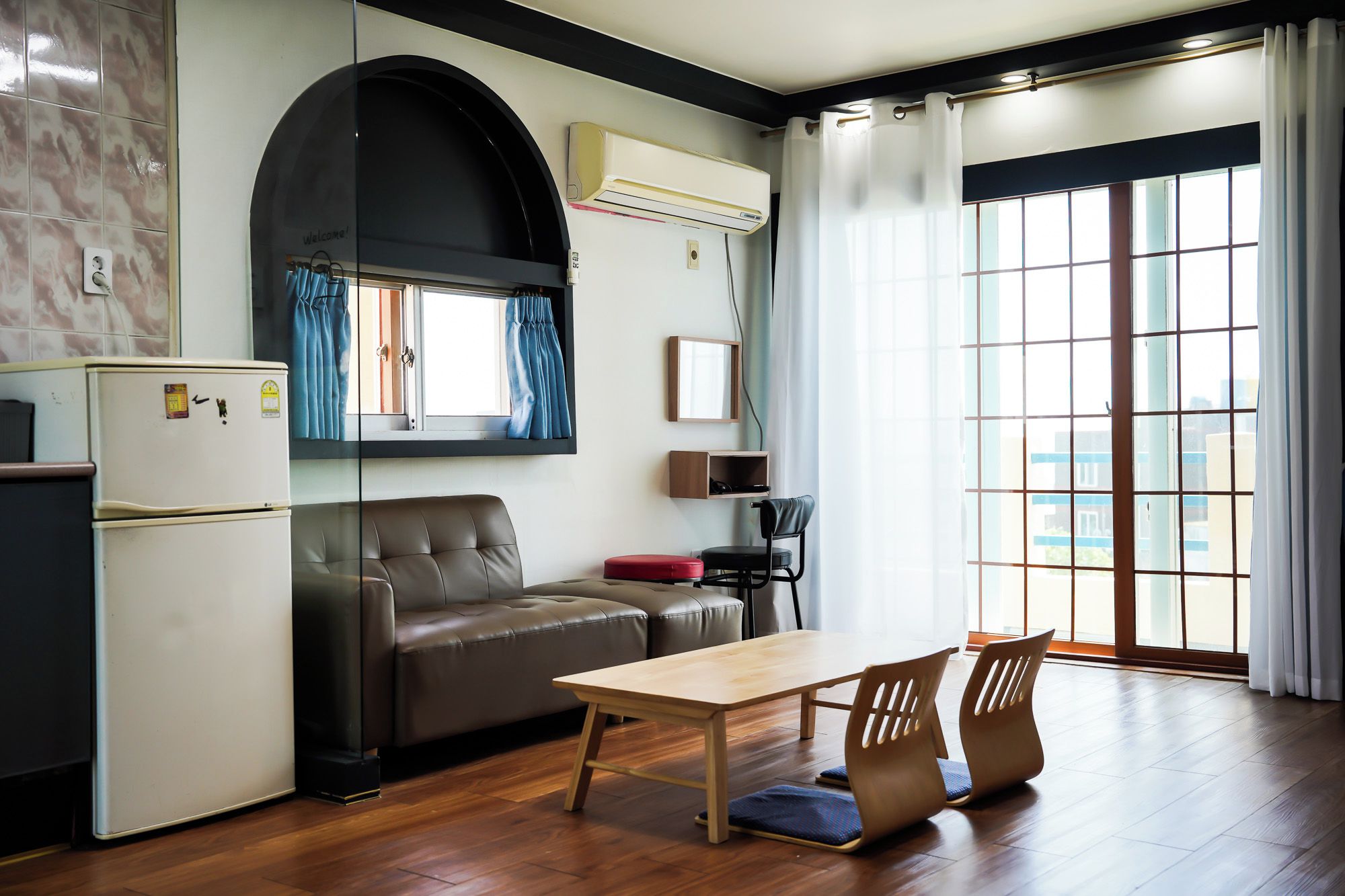 A compact living space with a kitchenette, a sofa, a dining table, and a chair.