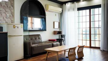 A compact living space with a kitchenette, a sofa, a dining table, and a chair.