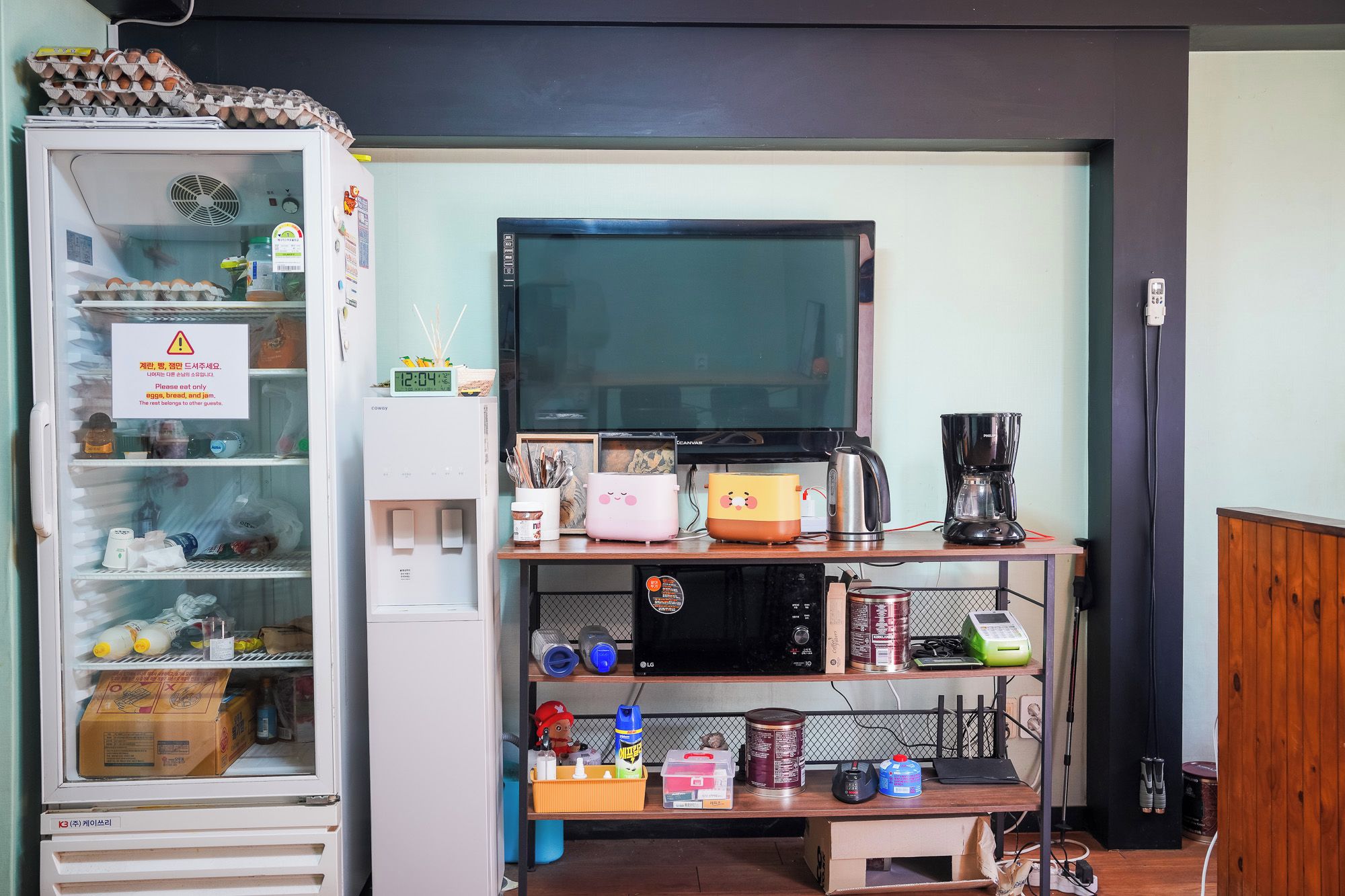 Une petite cuisine équipée d’un réfrigérateur, d’un four à micro-ondes, d’une machine à café et de divers produits alimentaires.