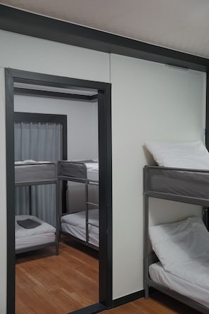 Une pièce avec des lits superposés, un rideau et un plancher en bois.