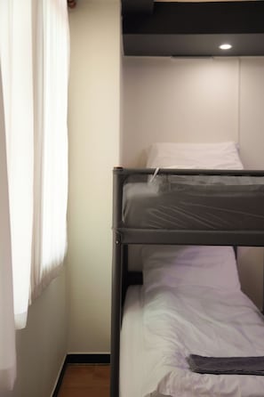 A bunk bed with a headboard, a white pillow, and a blanket.