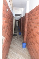 Un estrecho pasillo con paredes de ladrillo rojo y un piso con diseño, que conduce a una puerta al final.